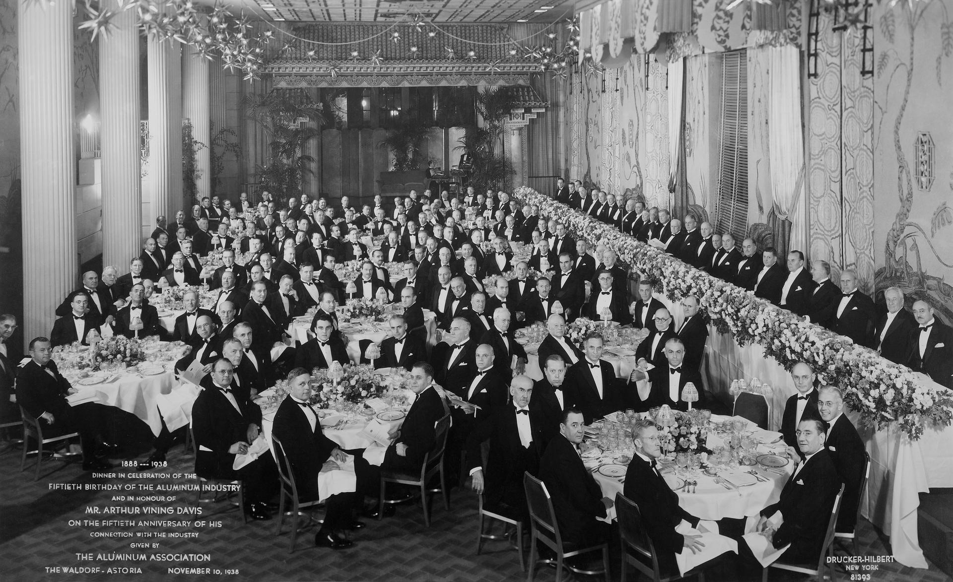Old black and white photo of businessmen in black tie attire at a company event 