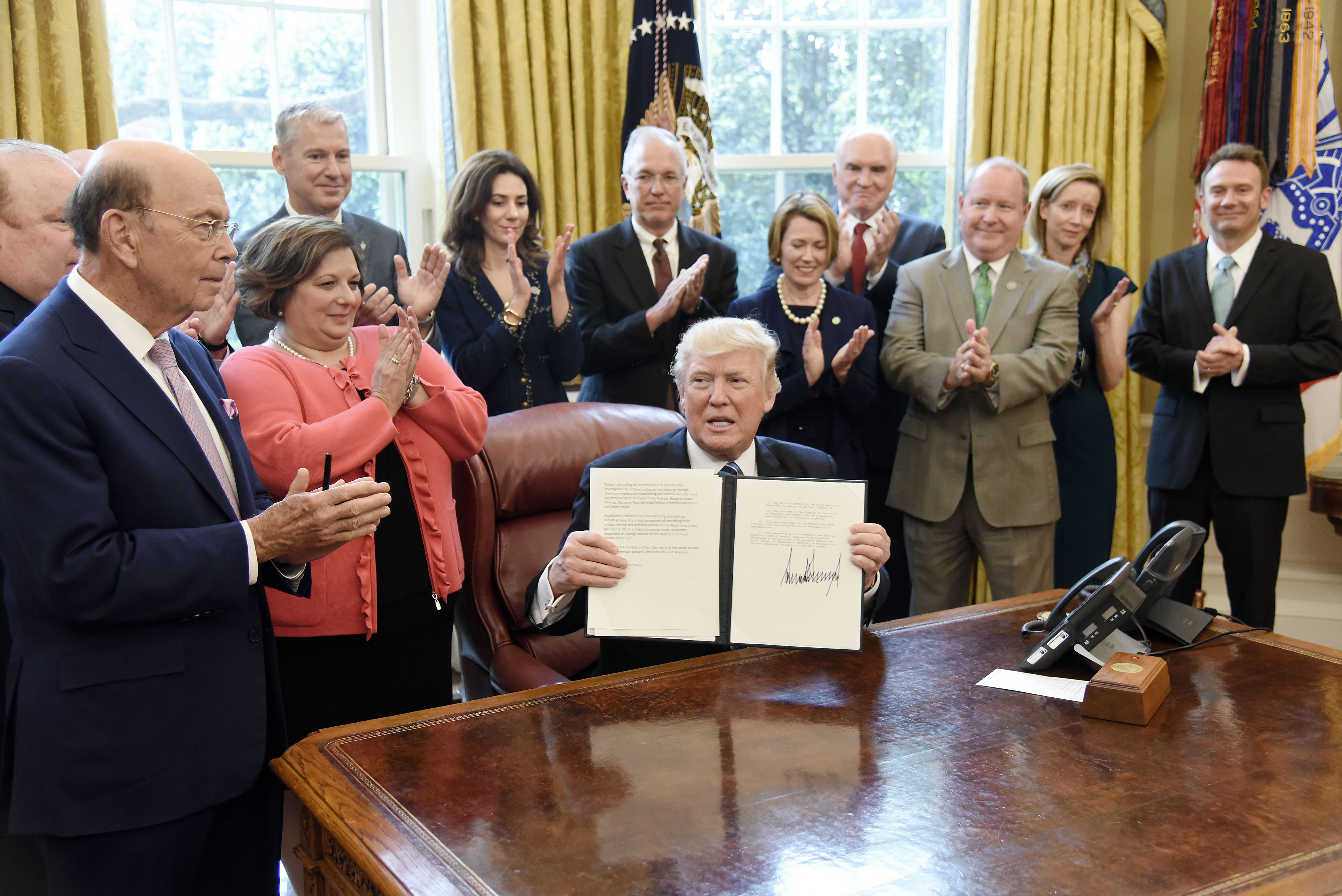 Photo of aluminum industry executives in the Oval Office Donald Trump holding up a signed executive order