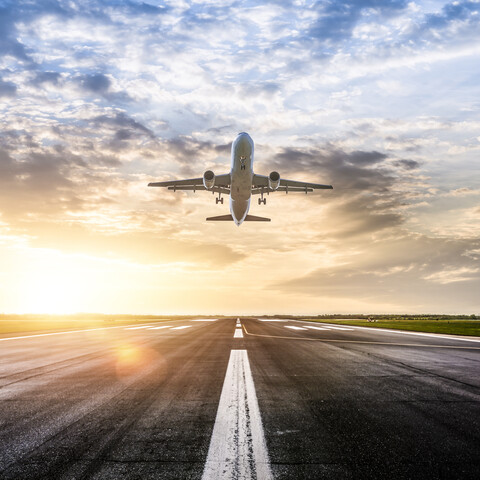 photo of a plane taking off at sunrise